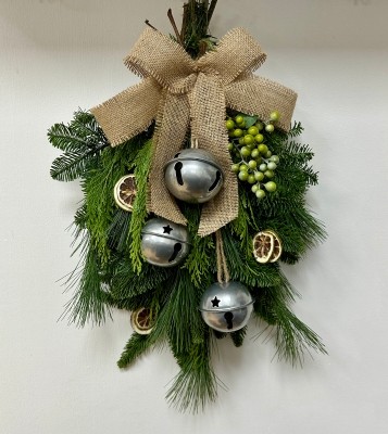 Natural door swag filled with winter foliage, green berries, lime slices, silver bells and a hessian bow. 