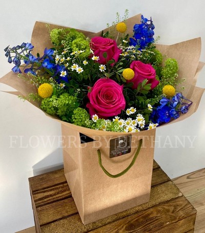 Make someone's day with this groovy bunch filled with roses, delphinium, craspedia, matricaria & more! 