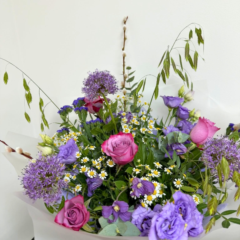 Lilac garden-inspired bouquet featuring seasonal lilac and purple florals with soft texture and natural movement, hand-tied with mixed foliage in a luxury lavender gift bag by Flowers by Bethany.