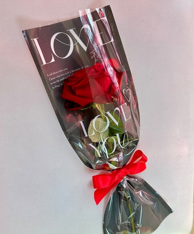  This charming single red rose, gracefully nestled in a paper wrap adorned with heartfelt words of love. 