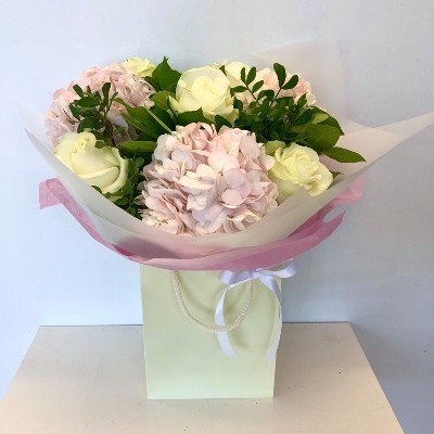 Hand tied bouquet of soft pink hydrangea and white roses, wrapped in luxury cellophane and a gift bag. 