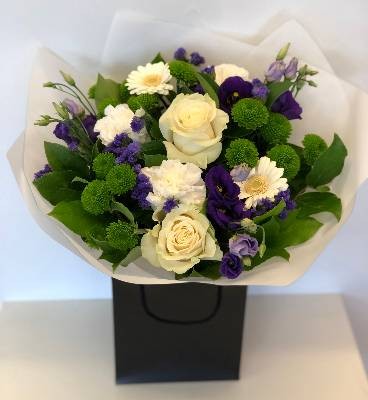 Hand tied bouquet including mondial white roses, purple Lizianthus, Kermit chrysanthemum and a mix of other fresh toned flowers. 