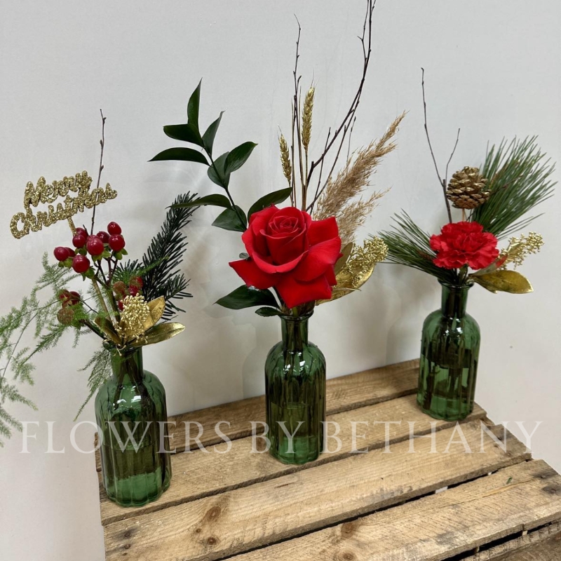 A trio of green glass vases, each filled with red florals, festive foliage and a sprinkle of gold décor. The perfect set for your table centrepiece this Christmas. 