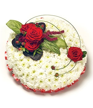 White chrysanthemum funeral posy with red ribbon edging and a red focal, complemented by lush foliage. Customizable color options available.
