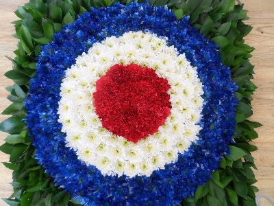 MOD Funeral tribute made with blue, white and red chrysanthemum and foliage background. 