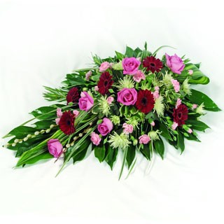 Single-ended spray with red and pink seasonal flowers and complementary foliage.