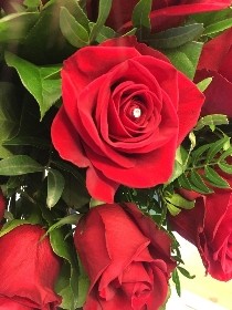 Eighteen luxury red Freedom roses, hand-tied in water, wrapped in modern cellophane, and presented in a signature black gift bag, with diamante rose centres for added sparkle.