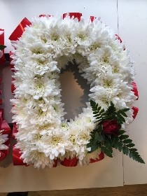 R KID Funeral lettering in traditional white massed chrysanthemum and red ribbon edge and focal. 