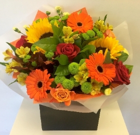 Autumn vibe bouquet in orange, yellow and green. Including roses, germini and sunflowers. 