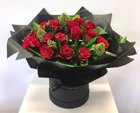 Luxury bouquet featuring large-headed red roses, skimmia, aspidistra folded leaves, and diamanté centres, wrapped in luxury cellophane and presented in a matching hat box, hand-tied in water.