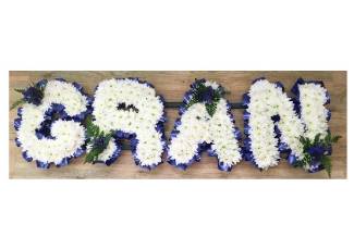 GRAN lettering, massed with white chrysanthemum and dark blue ribbon edging. 