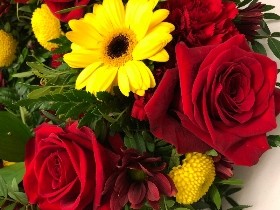 Red and yellow funeral wreath with seasonal flowers and foliage, a fitting tribute for any Manchester United fan.