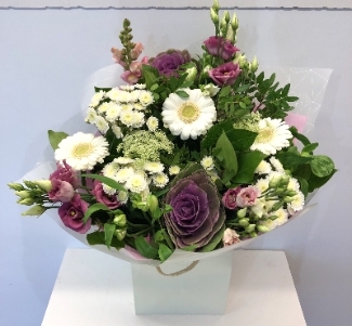Hand tied of natural flowers in pinks, whites and lilac including rose, brassica and chrysanthemums. 