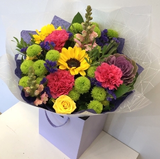Hand tied bouquet in water with a vivid mix of colour including roses, carnation, chrysanthemums and brassica. 