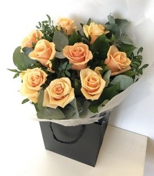 A gorgeous bouquet of 9 peach roses wrapped in cellophane in water. 