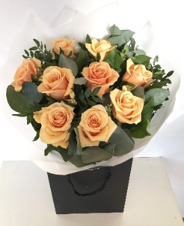 A gorgeous bouquet of 9 peach roses wrapped in cellophane in water. 