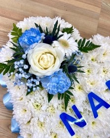 Heart-shaped funeral tribute with laminated wording, white chrysanthemums, delicate ribbon edge, and matching focal. Customizable colour options available.