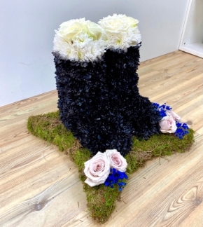 Wellington Boot funeral tribute on a moss base with black and white wellington boots