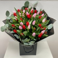 Bouquet of mixed red and pink tulips, accented with foliage and loose populous eucalyptus, wrapped in luxury cellophane and presented in a matching gift bag, hand-tied in water.