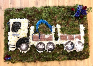 Lorry funeral tribute created with chrysanthemum and printed detailing on a bed of sheet moss. 