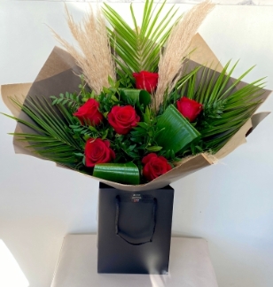 Luxury bouquet including stunning red roses and natural pampas grass, presented in craft paper and black gift bag. 