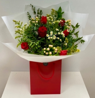 Natural bouquet filled with fresh meadow flowers and finished with rich red roses and mixed foliage. Wrapped in cellophane and presented in our signature gift bag in water. 