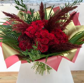 The ultimate gift of 50 Luxury red roses, adorned with pampas grass and high end foliage, wrapped in gold metallic cellophane, hand tied in water. 