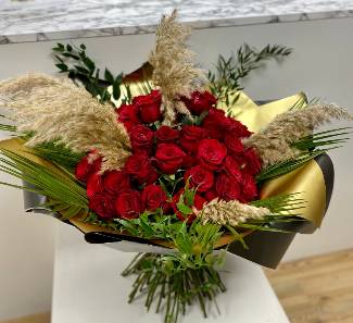 The ultimate gift of 50 Luxury red roses, adorned with pampas grass and high end foliage, wrapped in gold metallic cellophane, hand tied in water. 