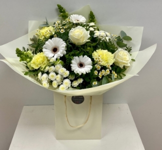 Soft yellow, cream and white toned bouquet filled with roses, carnations, germini and snapdragons hand tied in water. 