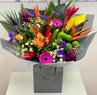 A stunning mix of English garden and Hawaiian tropic florals in a vibrant hand tied in water. 
