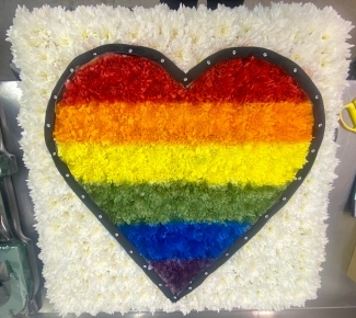 Pride flag funeral tribute in a heart shape with ribbon trim and diamante detailing. 