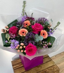 Peach and purple bouquet including allium, roses, germini, wax flower, stocks and more. Hand tied in water and presented in a gift bag. 