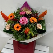 Hand tied gift bouquet in water. Design includes pink roses, orange germini, yellow solidago, orange celosia, peach carnation, oakleaf and spear palms. 