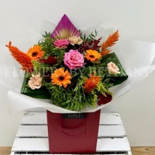 Hand tied gift bouquet in water. Design includes pink roses, orange germini, yellow solidago, orange celosia, peach carnation, oakleaf and spear palms. 