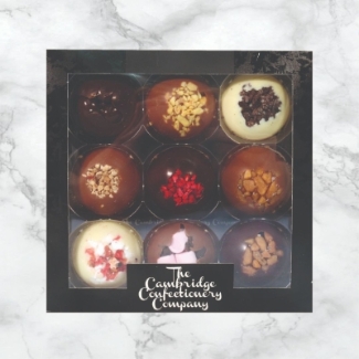Assorted luxury solid chocolate domes from The Cambridge Confectionery Co., featuring flavours like Dark Raspberry, Milk Honeycomb, Dark Salted Caramel, and more, arranged in gift boxes.