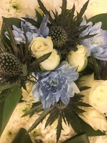 Boy teddy bear tribute with bow tie and blue accent flowers. 