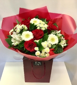 A gift bouquet including a mix of red and white flowers wrapped in our signature look.