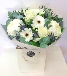 Hand tied with white blooms, roses,  germini and blue thistle with glitter. 