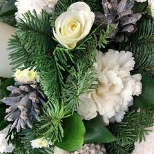 Festive table arrangement with white flowers and finished with a candle. 