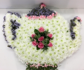 Teapot funeral tribute with delicate lilac and soft pink focal flowers. 