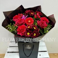 Sparkling bouquet featuring luxury red Freedom roses, red carnations, and red hypericum berries, accented with diamante centers, red glitter, and a pink butterfly, wrapped in luxury cellophane and matching gift bag, hand-tied in water.