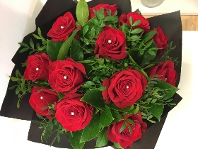 12 Luxury red roses with diamanté centre and complementary foliage presented in a matte black hat box. 