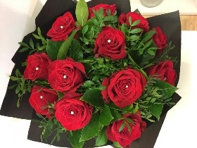 Twelve luxury large-headed red roses with complementary foliage and diamante centres, wrapped in matte black cellophane and presented in a signature matte black hat box. Also available in an 18-rose option.