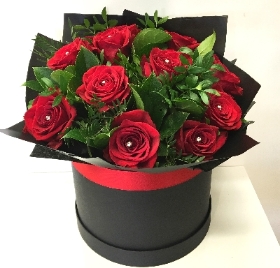 12 Luxury red roses with diamanté centre and complementary foliage presented in a matte black hat box. 