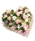 Loose floral heart tribute in soft pink and white tones. 