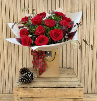 Luxury red rose Christmas bouquet with winter foliage and tartan festive accents.