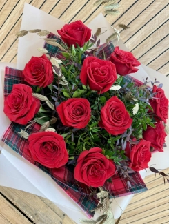 Luxury red rose Christmas bouquet with winter foliage and tartan festive accents.