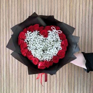 Valentine’s bouquet made with 24 premium red roses arranged around a white gypsophila heart with a pearl bow, wrapped in black with red ribbon, designed out of water with options for a gift bag with water bubble or upgrade to a modern glass vase.