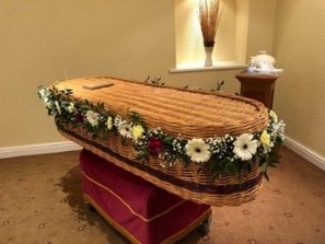 Delicate foliage and seasonal florals garland for wicker casket, customizable in colour and fullness.