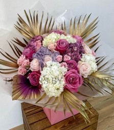 Elegant bouquet with roses, spray roses, and hydrangea, accented with gold leaf and an ombré palm, presented in a signature gift bag.
